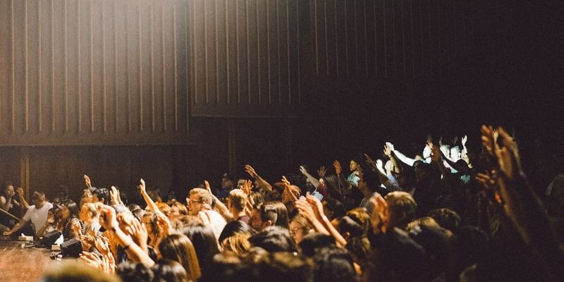 A crowd of people raises their hands in a church worship service