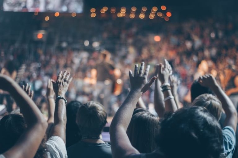 A group of church members raise their hands at a concert fellowship event