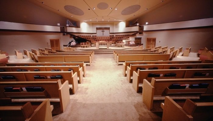 Interior of a church with wooden pews and beige carpeting and walls