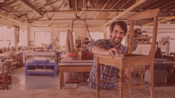 A man sands a wooden church chair frame