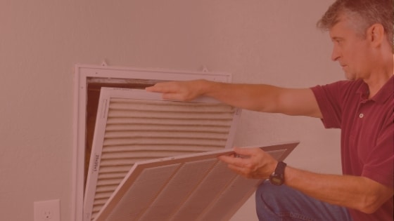 An HVAC technician changes the filter in an air vent