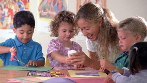 A church volunteer helps children glue construction paper during a Sunday School session