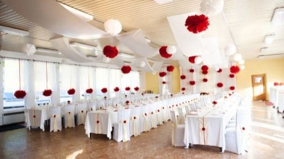 A wedding reception hall set up with rows of white tables and chairs